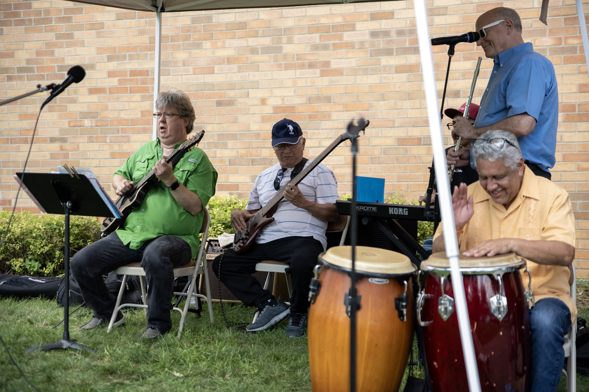 A group of musicians from the Tapestry congregation play outdoors beneath a portable awning